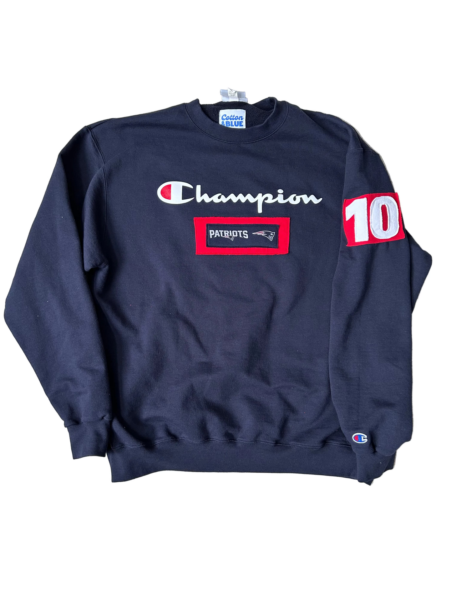 Navy blue sweatshirt with Champion logo and New England Patriots branding on a light gray background